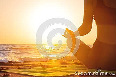 Close-up Yoga woman meditating at serene sunset or sunrise on the beach. The girl relaxes in the lotus position. Fingers Stock Photo