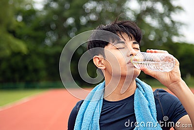 Close up young Asian teenages drinking water from bottle after run in park with copy space Stock Photo