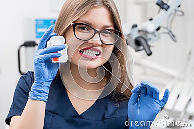 Portrait of attractive female dentist with dental floss in the dental clinic Stock Photo