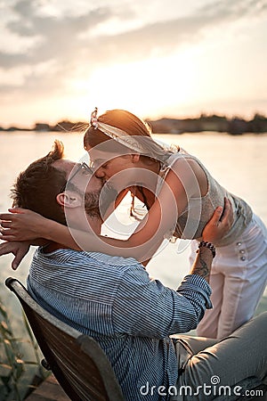 Close up of young beautiful caucasian female kissing a man on the riverside at sunset Stock Photo