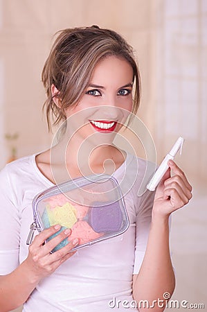 Close up of a young beautiful smiling woman holding a menstruation cotton tampon in her hand and a colorful purse inn Stock Photo