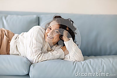 Close up of young Caucasian woman laying down on blue sofa indoor, fell asleep in casual outwear Stock Photo