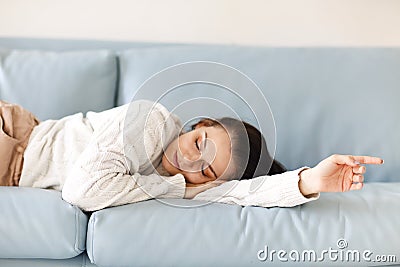 Close up of young Caucasian woman laying down on blue sofa indoor, fell asleep in casual outwear Stock Photo