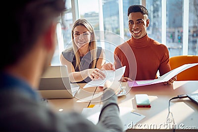Close-up of young colleagues in a commission having a pleasant talk with a young male applicant during an interview for a job. Stock Photo