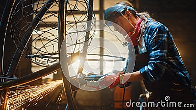 Close Up of Young Female Fabricator in Safety Mask. She is Grinding a Metal Tube Sculpture with an Stock Photo