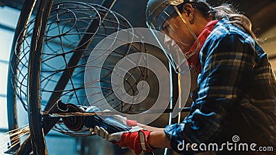 Close Up of Young Female Fabricator in Safety Mask. She is Grinding a Metal Tube Sculpture with an Stock Photo