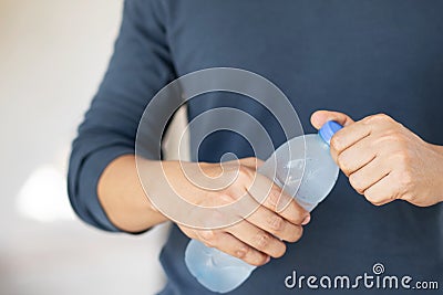 Close up young man hand holding cool fresh drinking water bottle from a plastic. Open up, drink, Stock Photo