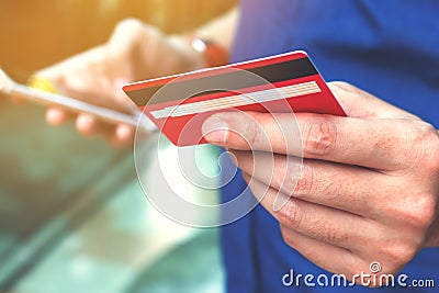 Close up of young man holding credit card and using smart phone Stock Photo