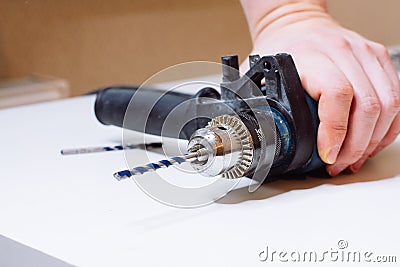 Close up of young man is preparing electric drill and changing drill bit Stock Photo