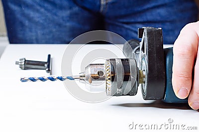 Close up of young man is preparing electric drill and changing drill bit Stock Photo