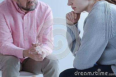 Close-up of a young sad woman sharing her grief with a psychotherapy specialist during an individual counseling meeting. Stock Photo