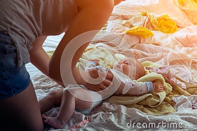 Mother swaddles and dresses a little baby girl Stock Photo