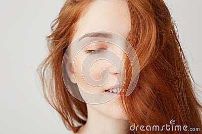 Close up of young tender beautiful girl with red hair smiling with closed eyes over white background. Stock Photo
