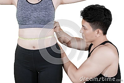 Trainer measuring slim waist of his client on studio Stock Photo