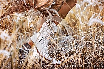 Close up of young woman legs wearing cowgirl boots on the field Stock Photo