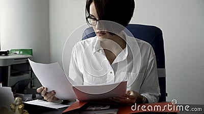 Close up for young woman in white shirt looking at laptop, answering the phone, and smiling on white office wall Stock Photo