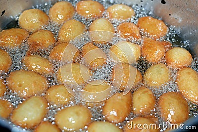 Zalabia a type of fried dough similar to that of a doughnut frying in boiling hot oil in a deep fryer at home Stock Photo