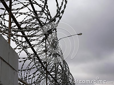 Close-up Ð²arbed wire on the background gray sky. Prison concept, space for text Stock Photo