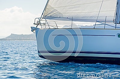Close view against the sun at sailboat bow with hoisted headsail. Stock Photo