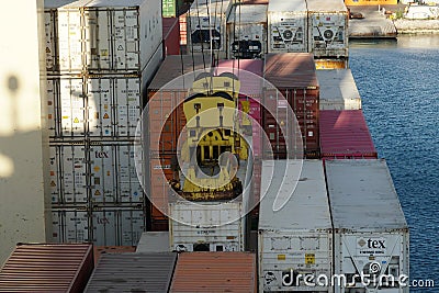 Close view on loading container attached to spreader of gantry cranes operated by stevedores Editorial Stock Photo