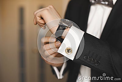 Close view of the luxury watches on the hand of a handsome businessman in a tuxedo and in a shirt with cufflinks Stock Photo