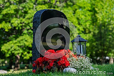 Black gravestone with red and white flowers Editorial Stock Photo