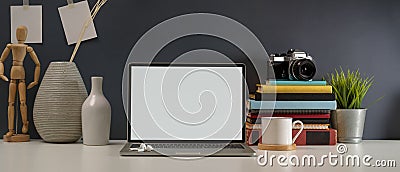 Study table with mock up laptop, stack of books, camera, supplies and decorations on white table Stock Photo