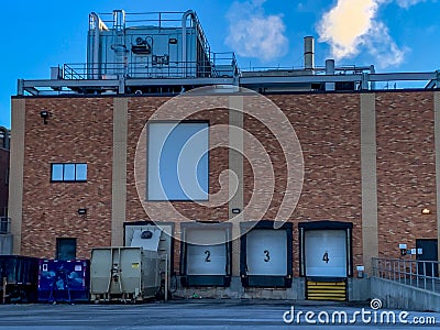 Closed bay doors and garbage roll-offs outside an industrial complex Stock Photo