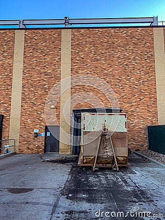 Closed bay doors and garbage roll-offs outside an industrial complex Stock Photo