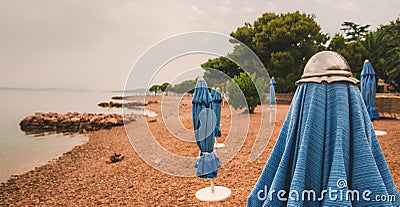 Closed beach parasol at empty seaside coast in Crikvenica, Croatia Stock Photo