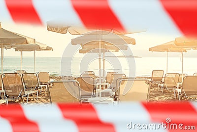 Closed beach. Sea, umbrellas and sunbeds with warning tape Stock Photo