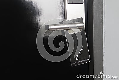 Closed black door of hotel room with please do not disturb sign on door handle Stock Photo