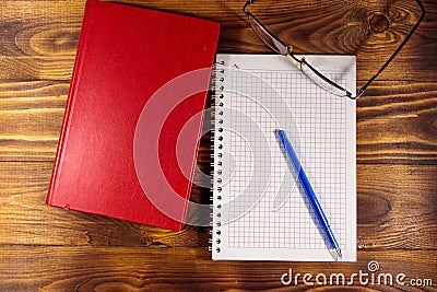 Closed book, eyeglasses, notepad and pen on wooden background Stock Photo