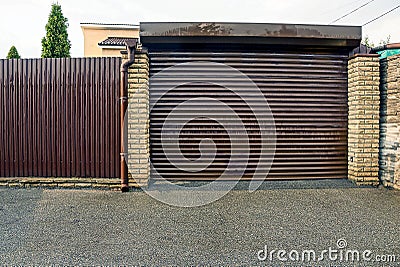 Closed brown gates in a private garage and part of an iron fence Stock Photo