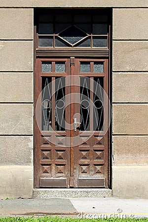 Closed brown wooden vintage old retro double entrance doors with decorative metal protection on front side of large family house Stock Photo