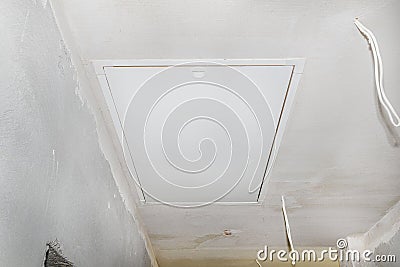 Closed entrance to the attic with a folding ladder in the ceiling of the house. Stock Photo