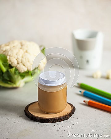 Closed glass jar with baby food cauliflower puree with fresh cauliflower and colored pencils. The concept of baby food Stock Photo