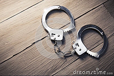 Closed handcuffs on a wooden background Stock Photo