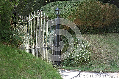 Closed iron driveway gates surrounded by shrubbery Stock Photo