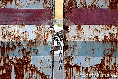 Closed and locked with strong metal chain and padlock old rusted backyard driveway doors preventing access to abandoned backyard Stock Photo