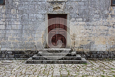 Closed obsolete wooden door and stone bricks steps ancient building Stock Photo