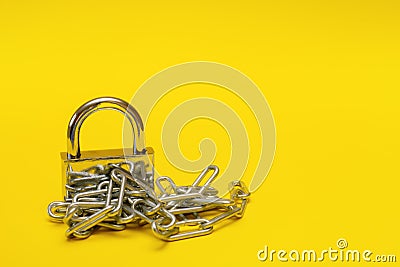 closed padlock with chain on yellow background with copy space, prohibition, taboo Stock Photo