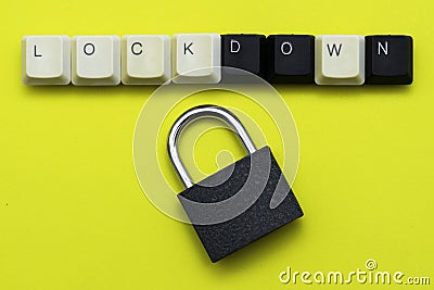 A closed padlock with keys on a yellow background at the top the inscription lockdown is laid out from the keys of a computer Stock Photo