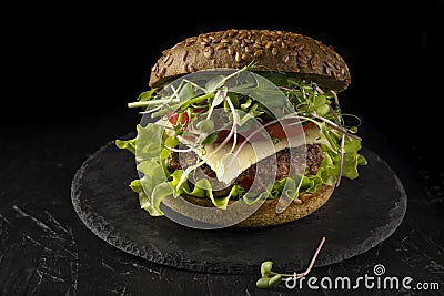 closed sandwich in a bun with cucumber, tomato and microgreens. Homemade burger. Stock Photo