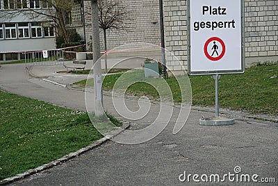 Closed school compound due to closed schools with coronavirus COVID-19 shield in German saying `place is blocked` meaning `no ent Stock Photo