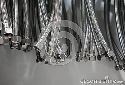 Closed up braided stainless steel texture of flexible hose arranged in a row against wall. Stock Photo