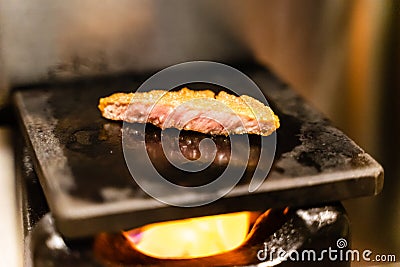 Closed up of fried pork meat grill on hot stone on small fireplace, very delicious traditional japanese food Stock Photo