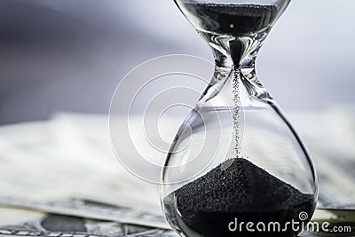 Closed up of sand falling in sandglass or hourglass on US Dollar Stock Photo