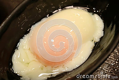 Closed up a soft-boiled egg served in a black stoneware bowl Stock Photo