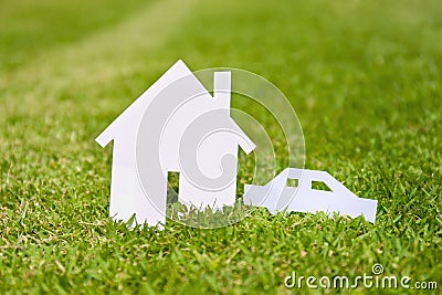 Closed up tiny home and car model from white paper on green grass background. Success dream life concept Stock Photo